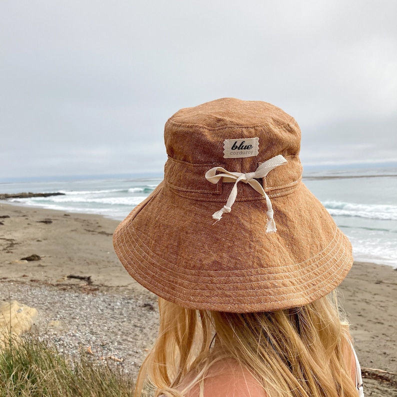 Wide brim rust colored homespun linen/cotton hand made sun hat for women. Sun hat has an adjustable tie made of cotton twill around crown of hat to adjust fit of hat. Brim can flip up or stay down with ease.