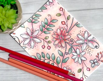 May include: A card with a pink and white floral pattern, with four coloured pencils on top.