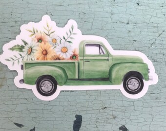 May include: A green vintage pickup truck with a bed full of white and yellow flowers. The truck has a white background.