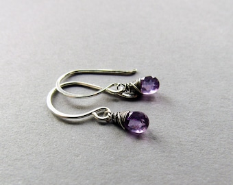 May include: A pair of silver earrings with small purple amethyst stones.