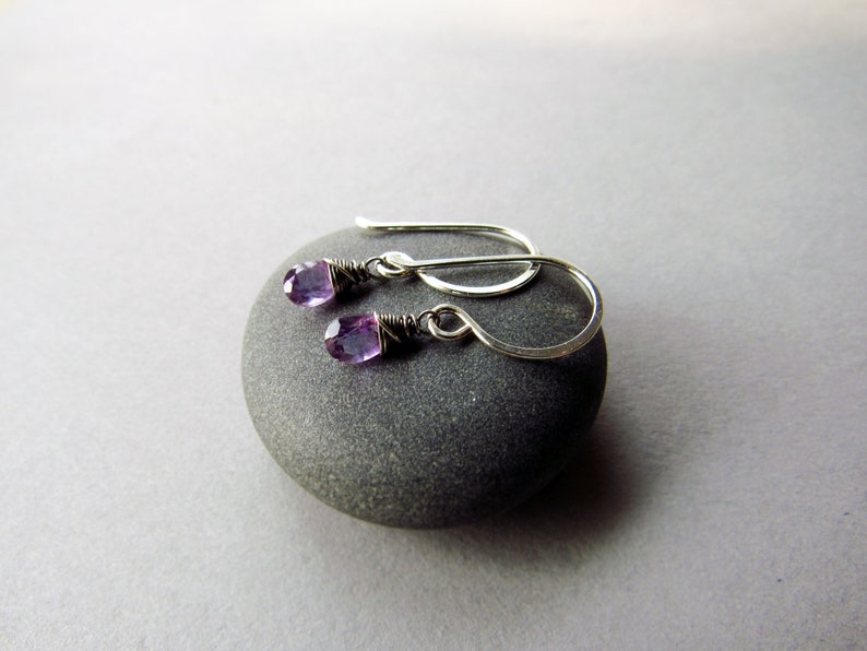 K&ouml;nnte beinhalten: Ein Paar silberne Ohrringe mit kleinen violetten Amethyststeinen, die unten h&auml;ngen.