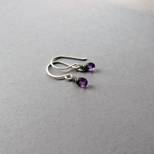 K&ouml;nnte beinhalten: Ein Paar silberne Ohrringe mit kleinen violetten Amethyststeinen.