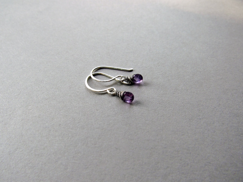 K&ouml;nnte beinhalten: Ein Paar silberne Ohrringe mit kleinen violetten Amethyststeinen.