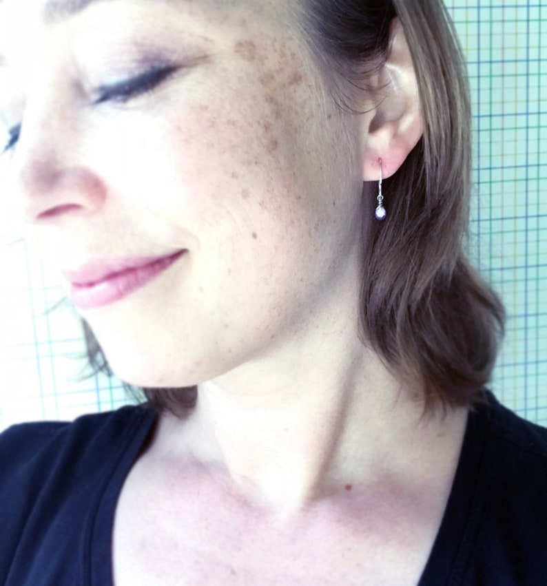 K&ouml;nnte beinhalten: Nahaufnahme eines Ohrs mit einem kleinen silbernen Ohrring mit einer einzelnen Perle, die daran h&auml;ngt.