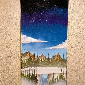 May include: A landscape painting depicting a night sky filled with stars above a mountain range and a waterfall. The sky transitions from black to blue, with white clouds. The mountains are brown, and the trees are green.