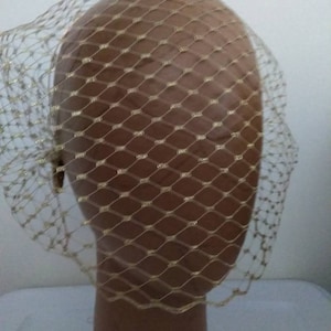 May include: A gold bridal veil with a delicate net pattern. The veil is made of a sheer fabric with a subtle shimmer.