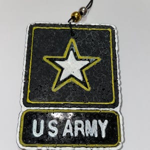 May include: Black and yellow US Army air freshener with a white star emblem. The air freshener has the words "US ARMY" in white lettering. The air freshener is rectangular with a black string for hanging.