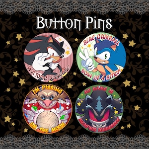May include: Four circular button pins featuring cartoon characters. One shows a black hedgehog with the text "HOT TOPIC WANNABE," another a blue hedgehog with "BLUE GUMBALL SON OF A BITCH," a third a mustachioed man with "I'M PISSING ON THE MOON," and the last a dark creature with "MY NAME IS MEMPHIS TENNESSGC."