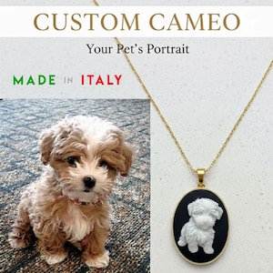 May include: A gold-colored necklace with a pendant featuring a white dog cameo on a black background. The image also shows a live dog and the text "CUSTOM CAMEO Your Pet's Portrait" and "MADE IN ITALY".