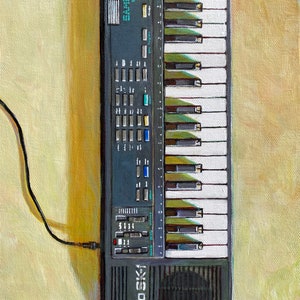 May include: A black Casio SK-1 keyboard with a white and black keyboard, a black speaker, and a variety of buttons and knobs. The keyboard is connected to a black cable.