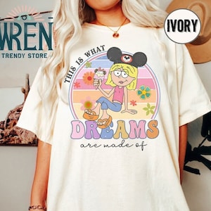 Puede incluir: Una camiseta blanca con un gr&aacute;fico de estilo retro que presenta a una ni&ntilde;a de dibujos animados con orejas de Mickey Mouse y sosteniendo un cono de helado. El gr&aacute;fico dice "This is what dreams are made of".