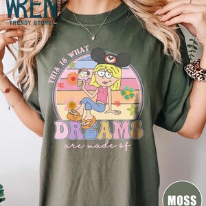 Puede incluir: Una camiseta verde con un gr&aacute;fico retro de una chica de dibujos animados con un sombrero de Mickey Mouse y sosteniendo un cono de helado. El gr&aacute;fico est&aacute; rodeado de flores y un arco&iacute;ris. El texto "This is what dreams are made of" est&aacute; escrito en una fuente colorida.