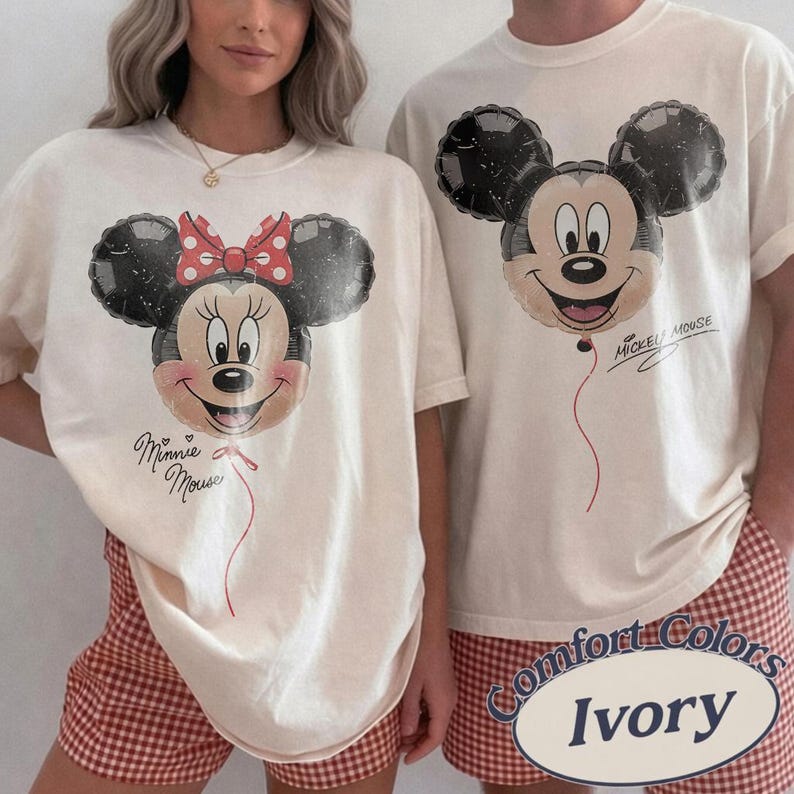 Op de afbeelding: Ivoor t-shirts met Mickey en Minnie Mouse ballonontwerpen. Minnie's ballon heeft een rode strik met witte stippen. De teksten "Minnie Mouse" en "Mickey Mouse" staan op de shirts. De shorts zijn rood-wit geruit.