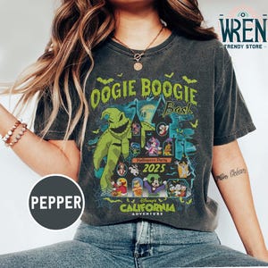 Puede incluir: Camiseta gris oscuro con un diseño para la fiesta de Halloween Oogie Boogie Bash en Disney's California Adventure en 2025. El diseño incluye el personaje de Oogie Boogie y otros personajes de Disney.