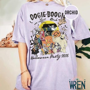 Puede incluir: Camiseta lila claro con un dise&ntilde;o de Halloween. El gr&aacute;fico incluye el texto "Oogie Boogie Bash" y "Halloween Party 2025", junto con ilustraciones de personajes como Jack Skellington y Sally.