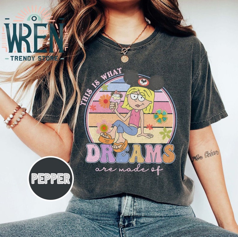 Puede incluir: Una camiseta negra con un gr&aacute;fico de estilo vintage que presenta a una ni&ntilde;a de dibujos animados con una diadema de orejas de Mickey Mouse sosteniendo un cono de helado. El gr&aacute;fico dice "This is what dreams are made of".