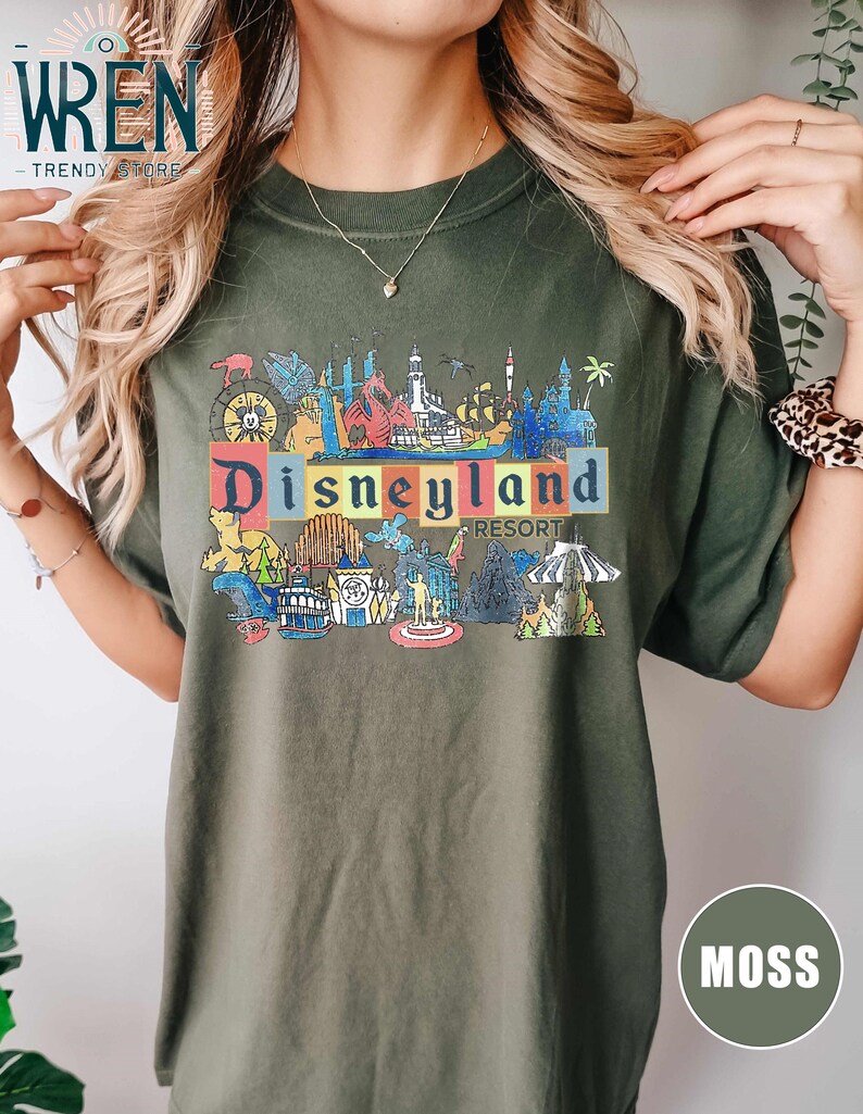 May include: A green t-shirt with a graphic print of the Disneyland Resort logo and various attractions. The text "Disneyland Resort" is printed in colorful letters.