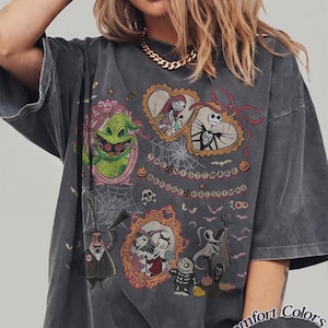 May include: Dark grey t-shirt featuring characters from "The Nightmare Before Christmas." The design includes images of Jack Skellington, Sally, Oogie Boogie, and Zero, with the text "The Nightmare Before Christmas."
