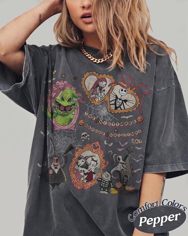 May include: Dark grey t-shirt featuring characters from "The Nightmare Before Christmas." The design includes images of Jack Skellington, Sally, Oogie Boogie, and Zero, with the text "The Nightmare Before Christmas."