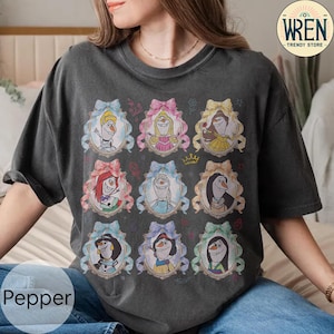 Puede incluir: Camiseta gris oscuro con retratos de dibujos animados de personajes animados en marcos ornamentados. Los retratos incluyen personajes con varios peinados y atuendos, sobre un fondo oscuro. La camiseta tiene el texto "Pepper" en la parte inferior izquierda y un logo "Wren Trendy Store".