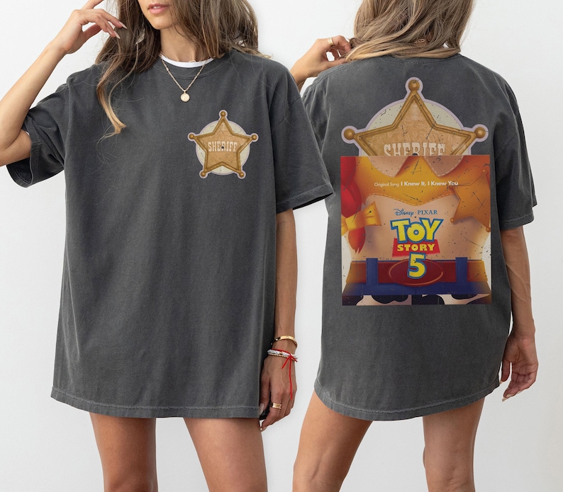 Puede incluir: Una camiseta gris carb&oacute;n con una peque&ntilde;a insignia de estrella de sheriff dorada en el pecho izquierdo. La parte posterior muestra una gran estrella de sheriff dorada sobre un gr&aacute;fico de un torso de personaje con el texto Disney Pixar Toy Story 5.