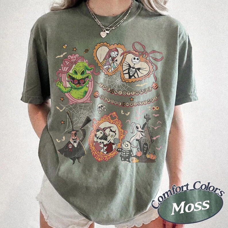 May include: A moss green t-shirt featuring characters from "The Nightmare Before Christmas." The design includes framed portraits of characters like Jack Skellington, Sally, and Oogie Boogie, with the film's title in a circular arrangement.
