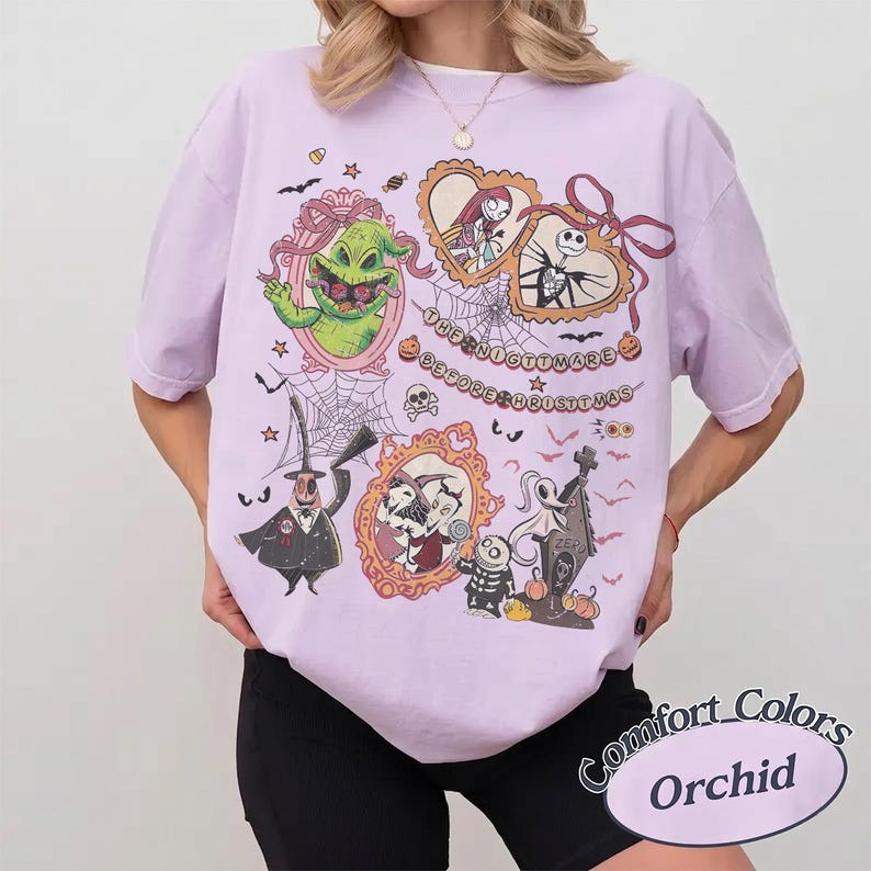 May include: Orchid-colored t-shirt featuring characters from "The Nightmare Before Christmas." The design includes framed portraits of characters, spiderwebs, and the text "The Nightmare Before Christmas." The shirt is a Comfort Colors brand.