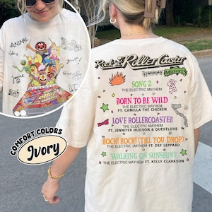 May include: Ivory t-shirt with a graphic of Muppets characters and the text "Rockin' Roller Coaster." The back of the shirt lists song titles and performers. The shirt also has the text "Comfort Colors."