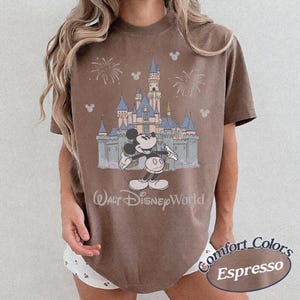 May include: Espresso-colored t-shirt featuring a graphic of Mickey Mouse in front of Cinderella's castle at Walt Disney World. The shirt has a vintage look with the words "Walt Disney World" printed below the castle.