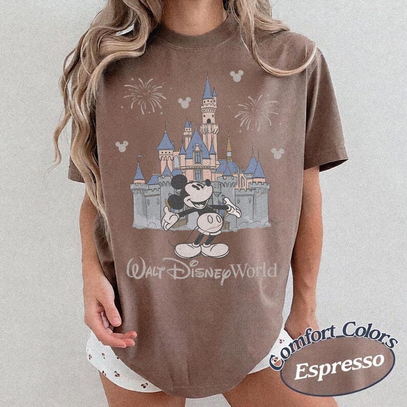 May include: Espresso-colored t-shirt featuring a graphic of Mickey Mouse in front of Cinderella's castle at Walt Disney World. The shirt has a vintage look with the words "Walt Disney World" printed below the castle.
