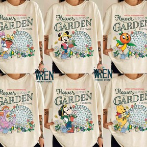 Puede incluir: Seis camisetas blancas con diferentes diseños de personajes de Disney. Cada camiseta tiene el texto "EPCOT International Flower & Garden Festival 2025".