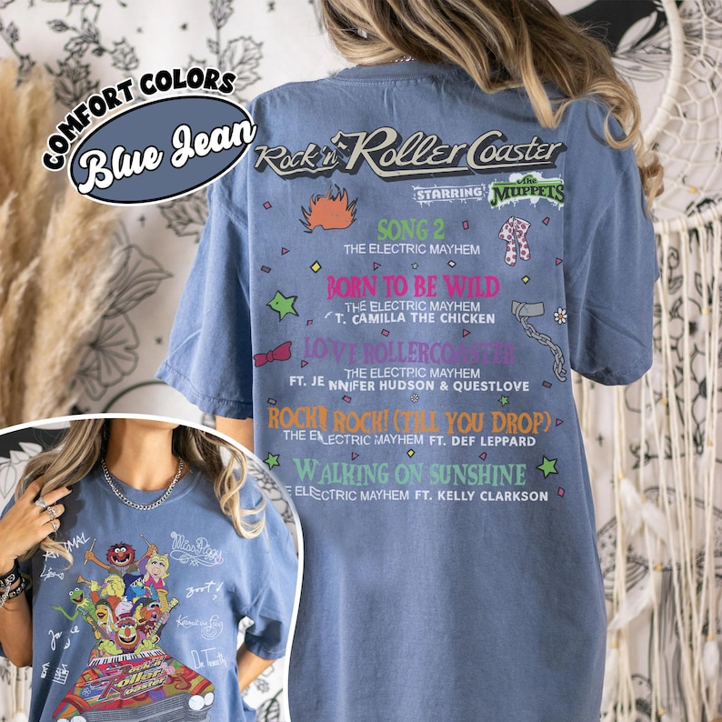 May include: Blue jean comfort colours t-shirt featuring a graphic of the Muppets' Rock 'n' Roller Coaster. The back of the shirt lists song titles like "Born to be Wild" and "Walking on Sunshine".