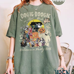 Puede incluir: Camiseta verde musgo con un dise&ntilde;o de Halloween. El dise&ntilde;o incluye el texto "Oogie Boogie Bash" y "Halloween Party 2025". El gr&aacute;fico presenta a Jack Skellington y otros personajes. La camiseta es de Wren Trendy Store.