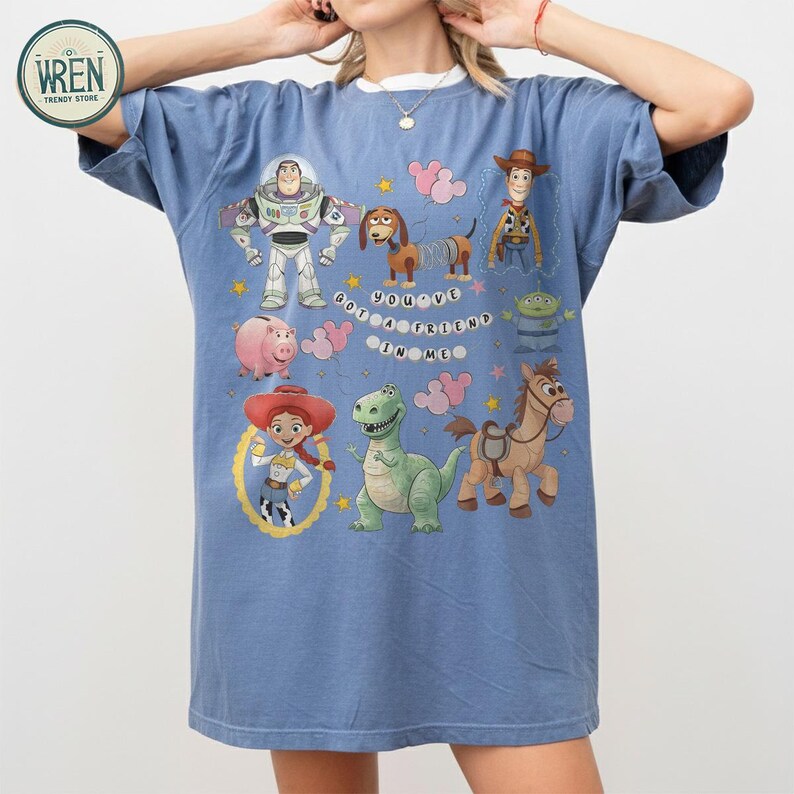 May include: Blue t-shirt with a crew neck and short sleeves, featuring cartoon characters from Toy Story. The graphic includes Buzz Lightyear, Woody, Jessie, and the text "You've Got a Friend in Me."