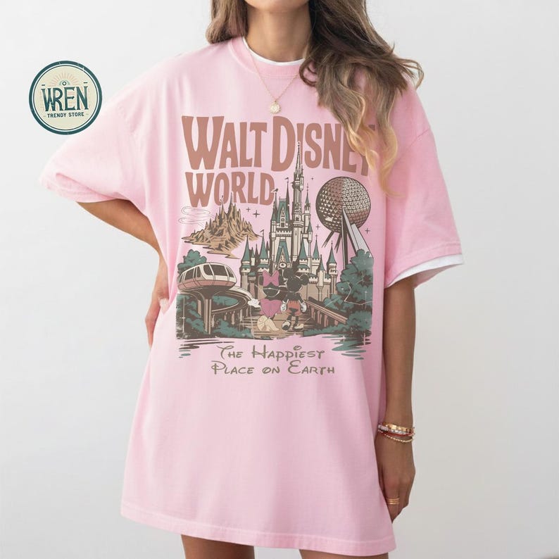 Może przedstawiać: Jasnor&oacute;żowa koszulka z grafiką Walt Disney World, w tym zamkiem, Spaceship Earth i napisem "The Happiest Place on Earth". Koszulka ma białe wykończenie na rękawach i kołnierzu.