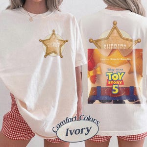 Puede incluir: Una camiseta color marfil con un gr&aacute;fico de estrella de sheriff dorada en el pecho izquierdo. La parte posterior muestra una gran estrella de sheriff dorada sobre un gr&aacute;fico de Toy Story 5, con el texto Disney Pixar Toy Story 5 e I Knew It, I Knew You.