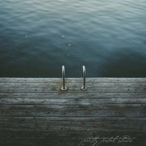 a wooden dock with two metal railings next to a body of water