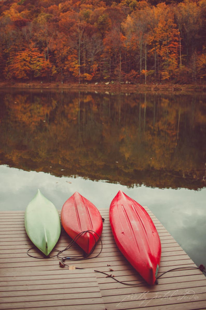 two red and green canoes sitting on a dock next to a lake