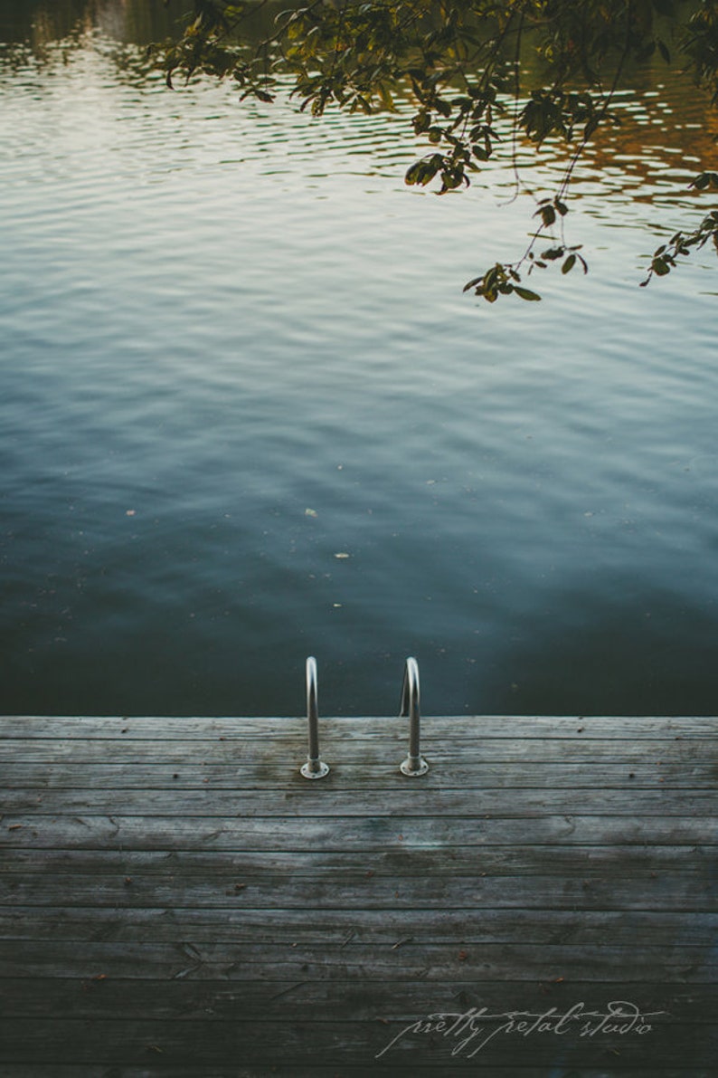 a wooden dock with two metal railings next to a body of water