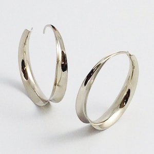 May include: A pair of silver hoop earrings with a smooth, curved design.