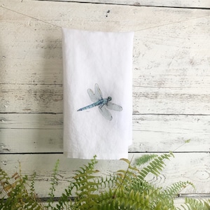 May include: White kitchen towel with a blue dragonfly illustration.
