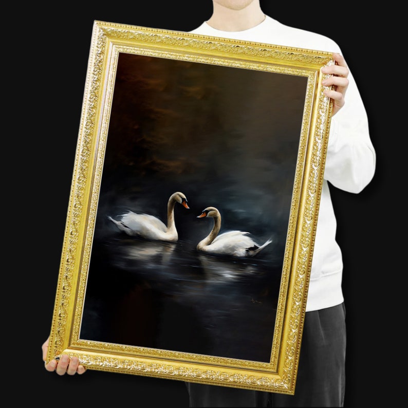 May include: A framed painting featuring two white swans on a dark, reflective body of water. The swans face each other, their necks curved. The ornate gold frame adds a classic touch to the artwork.
