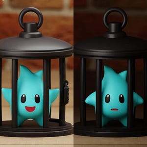 Könnte beinhalten: Ein schwarzer Käfig mit einer blauen sternförmigen Figur darin. Die Figur hat einen fröhlichen Gesichtsausdruck mit einem roten Mund und schwarzen Augen.