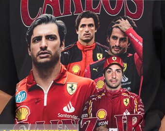 Op de afbeelding: Zwart T-shirt met een rode en witte afbeelding van Formule 1-coureur Carlos Sainz Jr. De afbeelding toont Sainz Jr. en andere coureurs in hun Ferrari-racepakken. De tekst "Carlos Sainz Jr." is in rood en wit gedrukt.