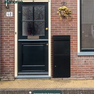 May include: A black metal parcel delivery box with a white label that reads "Cappadocia Extra Large Parcel Delivery Box" mounted on a brick wall next to a black door with a frosted glass panel. The house number 48 is visible on the wall.