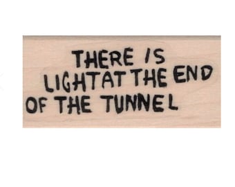 Puede incluir: Un sello de madera con el texto "There is light at the end of the tunnel" en tinta negra.