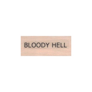 May include: A wooden stamp with the text "BLOODY HELL" printed in black ink.