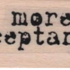 May include: A wooden stamp with the text "more acceptance" in black ink.