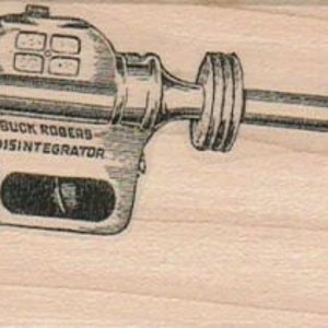 Könnte beinhalten: Eine Schwarzweißillustration einer Spielzeug-Strahlenpistole mit der Aufschrift "BUCK ROGERS DISINTEGRATOR" auf der Seite.