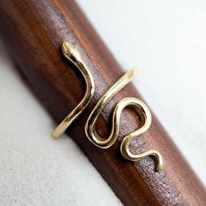 Peut inclure: Une bague en forme de serpent en or avec un design simple. La bague est en laiton et est un excellent moyen d'ajouter une touche de style à n'importe quelle tenue.